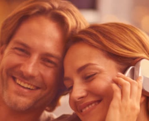 A smiling couple listening to a song together on headphones